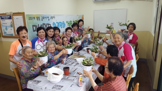 지난해 7월 자원봉사 프로그램 지원단체인 ‘알쏭달쏭 동아리’가 혜명양로원 어르신들과 함께 미세먼지 환경정화 식물 만들기를 하고 있다. (사진=금천구)